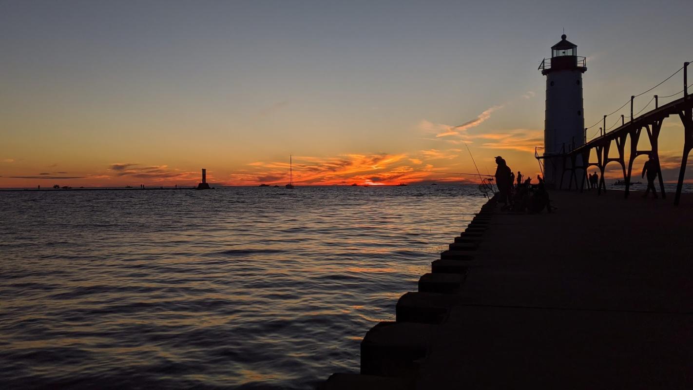 Picture of Lake Michigan at sunset with silhouetted dock and lighthouse. Credit Jennifer Schlicht