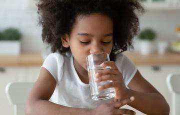 Image of a girl drinking a glass of water. Source: Canva