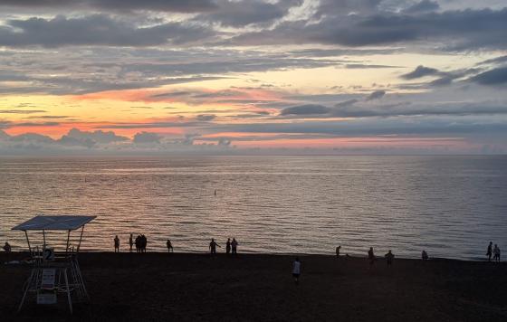 Lake Huron at sunset with silhouetted people and lifeguard stand.